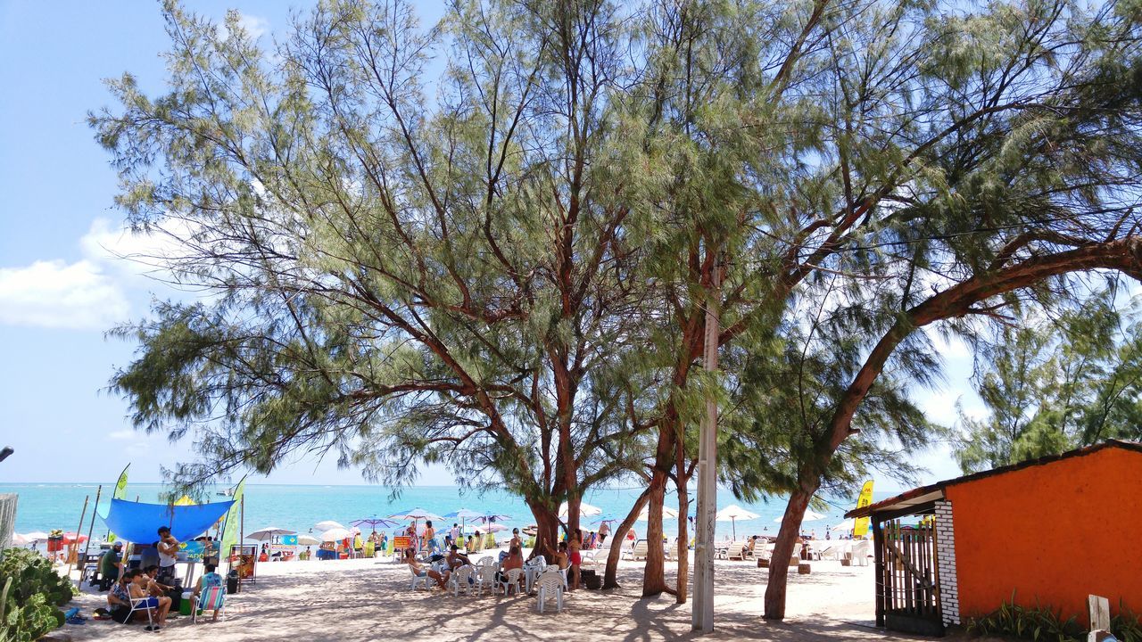 PANORAMIC VIEW OF PEOPLE ON SEA SHORE AGAINST SKY