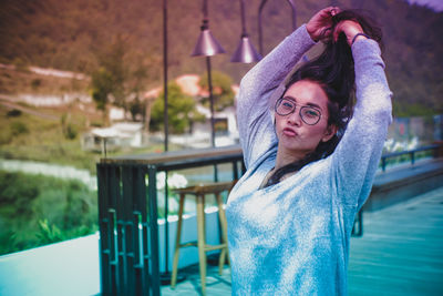 Portrait of young woman puckering while standing with arms raised