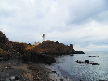 Lighthouse by sea against sky