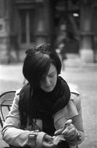 Young woman sitting on chair by street