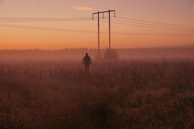 Man standing on field against sky during sunset