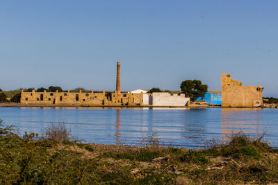 Old buildings by lake against clear sky