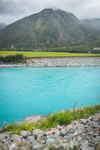 Scenic view of sea by mountains against sky