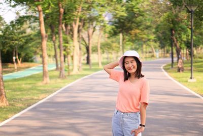 Portrait of woman standing on road against trees