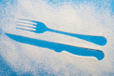 The imprint of the fork and knife on a blue colored surface