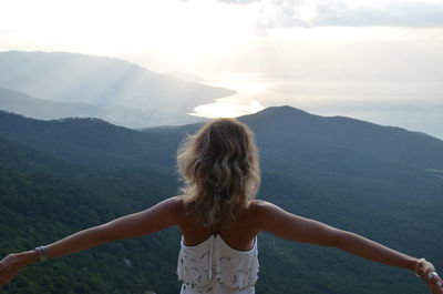 Rear view of woman standing on mountain against sky