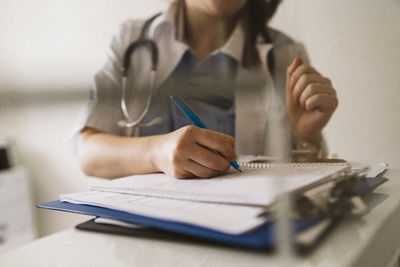 Midsection of female healthcare worker writing prescription