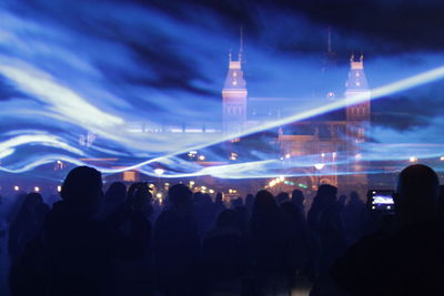 People against illuminated amsterdam central railway station with blue smoke during event