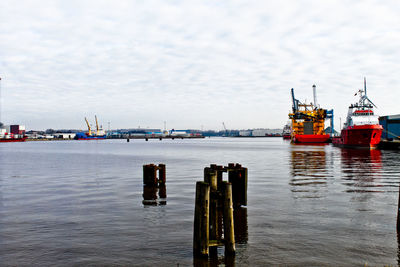 Boats moored at harbor against sky