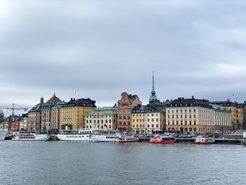 Buildings by river against sky