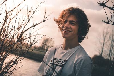 Portrait of smiling young woman standing against sky