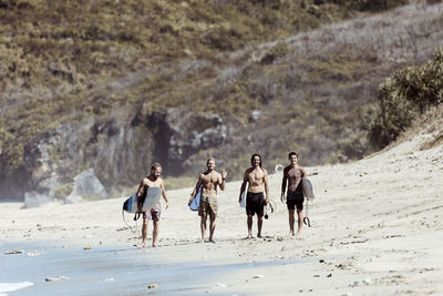 Male surfers standing on beach