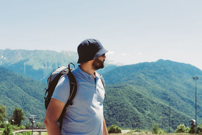 Young man standing against mountain