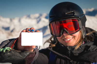 Winter sports girl holding a ski pass and smiling. a concept illustrating the entry fee for skiing