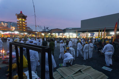 Crowd at illuminated city against clear sky at dusk