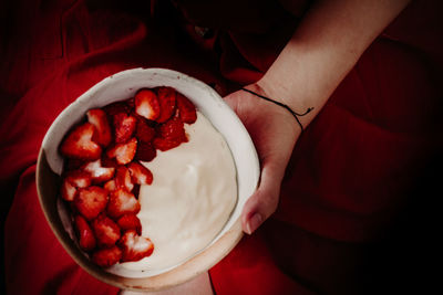 High angle view of hand holding strawberries in bowl