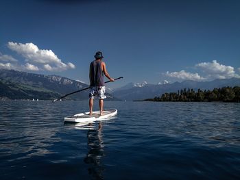 Rear view of man standing in sea against sky