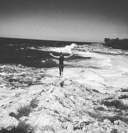 Rear view of woman standing on beach against sky