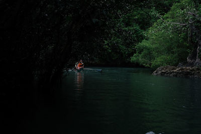 People in boat on lake against trees