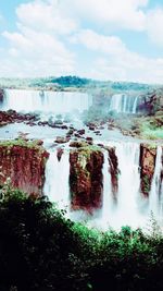 Scenic view of waterfall against cloudy sky