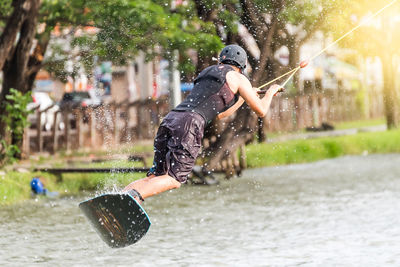 Man surfing in lake against trees