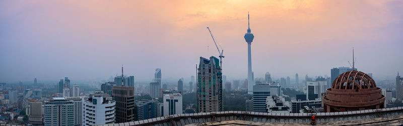 Modern buildings in city against sky during sunset