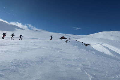 People walking on snowcapped mountain against sky