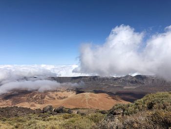 Smoke emitting from volcanic landscape against sky