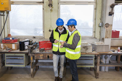 Manual workers repairing machine part in factory