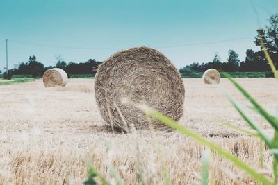 Hay bales on field against clear sky