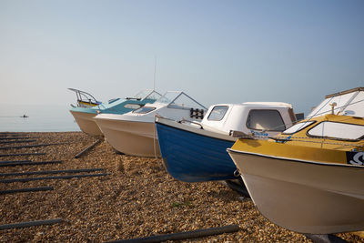 Boats moored on beach against clear sky