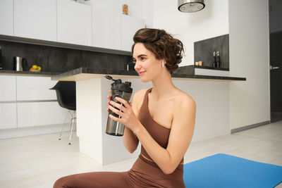 Young woman using mobile phone while sitting on floor at home