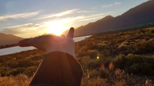 Midsection of person against sky during sunset