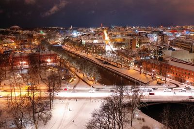 High angle view of illuminated city by buildings at night