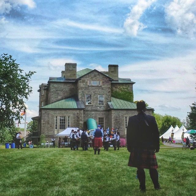 grass, men, large group of people, building exterior, architecture, lifestyles, person, leisure activity, built structure, sky, cloud - sky, green color, field, lawn, walking, grassy, tree, togetherness, mixed age range