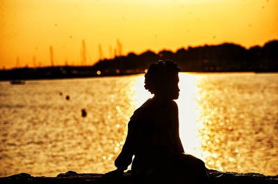 Silhouette man looking at sea against sky during sunset