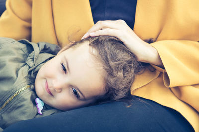 Close-up of cute daughter lying on mother laps