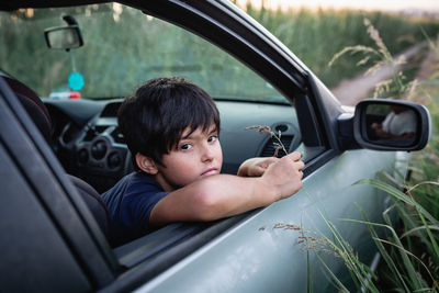 Thoughtful girl with short dark har watching from family car windows