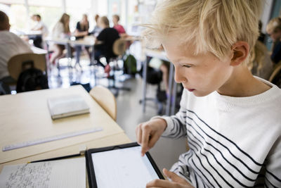 Boy using digital tablet at desk in classroom