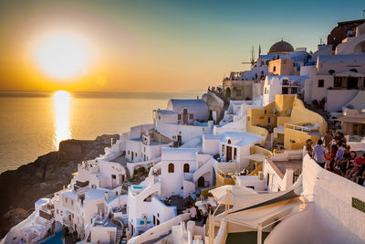 Tourists looking at the amazingly beautiful sunset at la caldera in oia city in santorini island