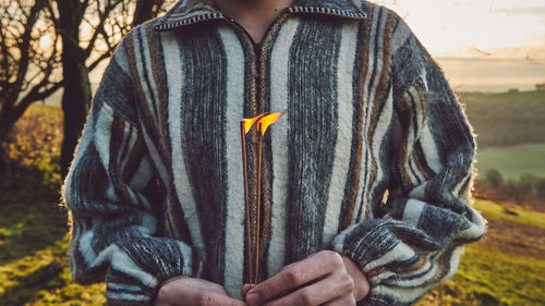 Midsection of person holding incenses