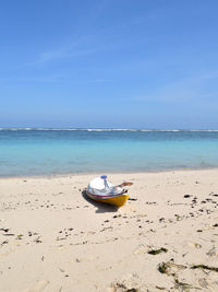 Boat moored on beach against sky