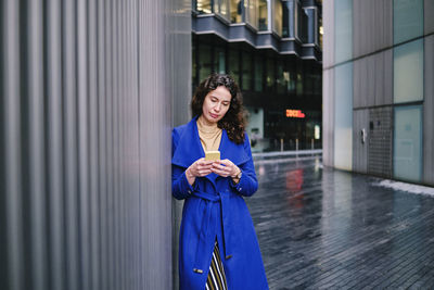 Young woman using phone while standing in city