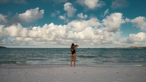 Woman standing at beach against sky