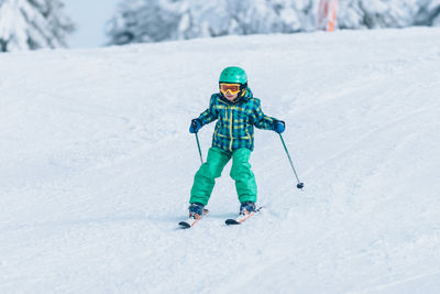 Full length of boy skiing on snow covered land