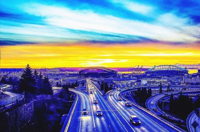 View of illuminated cityscape against cloudy sky