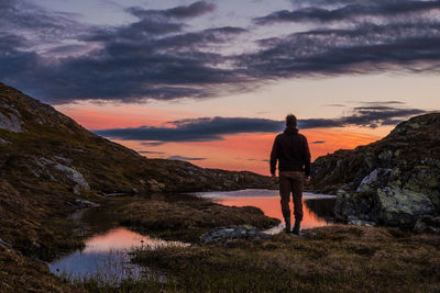 Rear view of man standing against sky during sunset