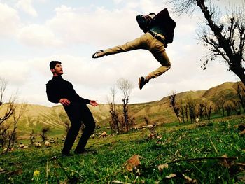 Full length of young man jumping on field against sky