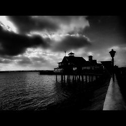 Pier on sea against cloudy sky