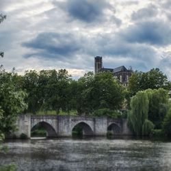 Bridge over river against cloudy sky